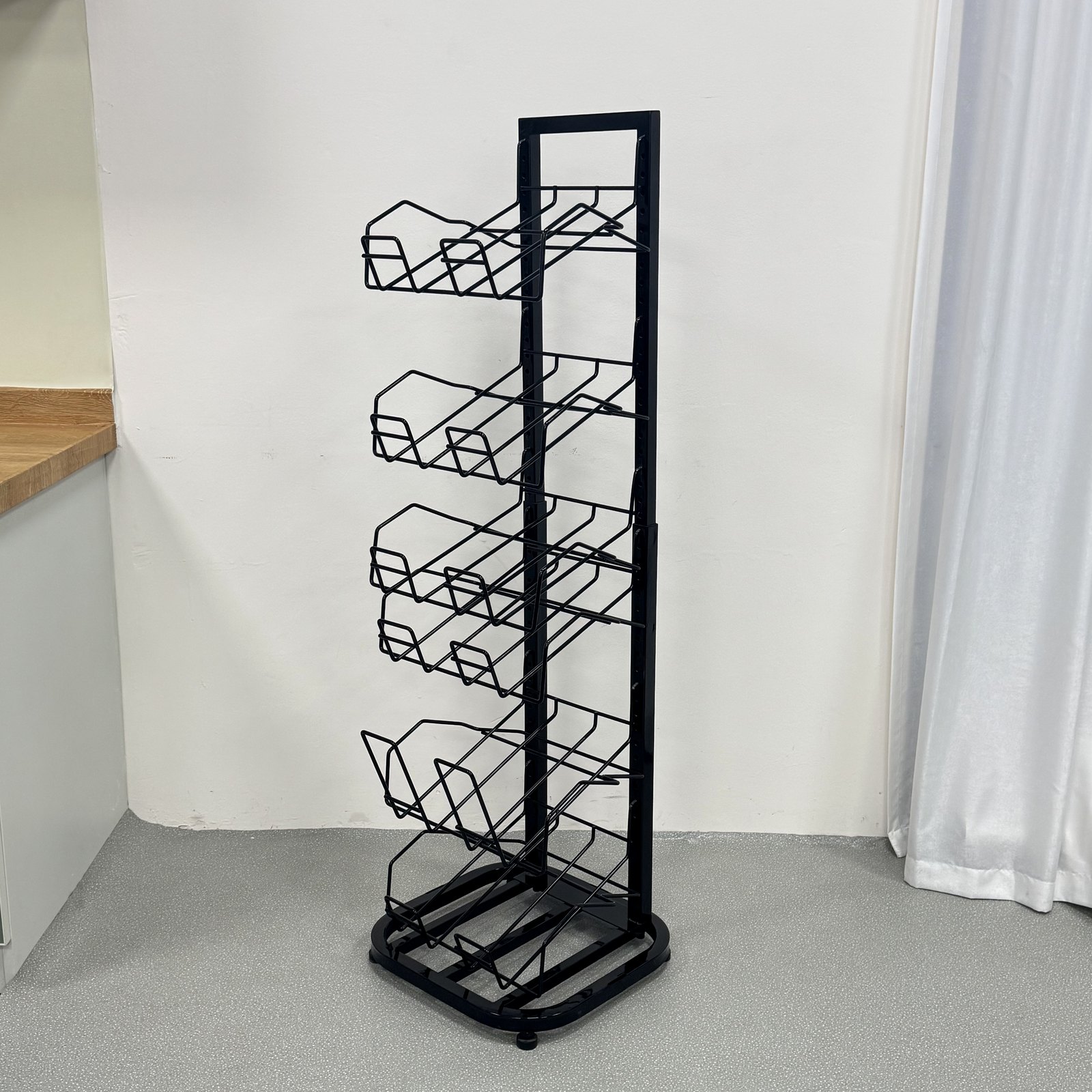 Black metal floor-standing newspaper and magazine display rack with multiple slanted wire pockets