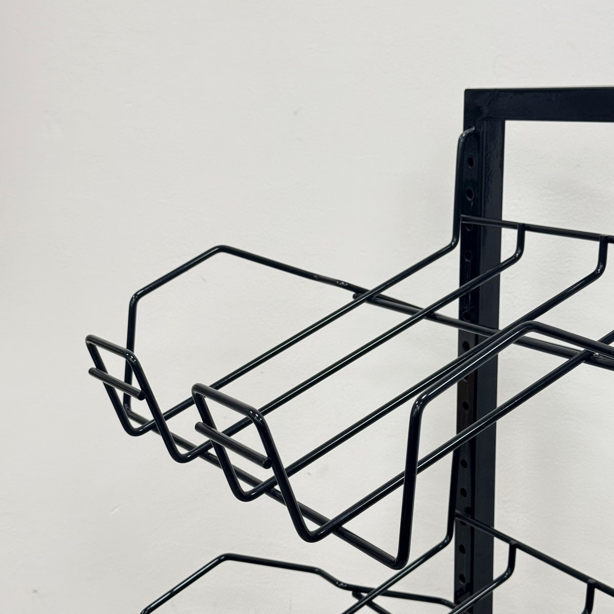 Close-up of slanted wire pockets on a black magazine display rack keeping front covers visible